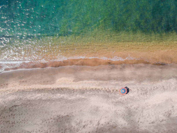 istock A lone beach umbrella on the sand beach, flat aerial view for background 1153479089