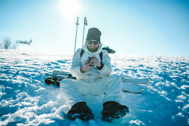 buon maschio che cerca diverse tecniche di sci su smartphone !!! - cold discussion outdoors snow foto e immagini stock