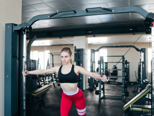 istock Blond fit woman doing exercise in crossover machine at gym 1153481265