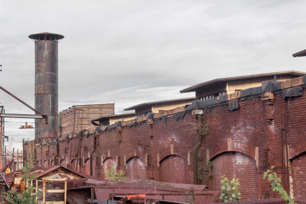 Exterior view of a warehouse district, old brick architecture, smokestack, rusting metal structures, horizontal aspect