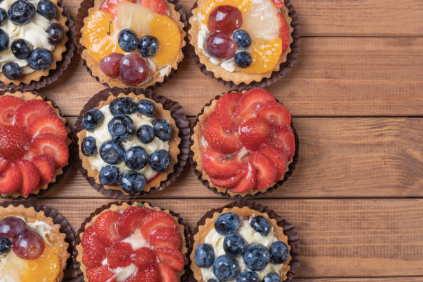 istock fruit tartlets on a wooden plate on the table, fruit baked shell, fruit cupcake with berry 1153488121