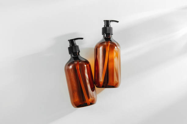frascos marrons transparentes para o champô, o sabão ou o outro cosmético no fundo branco. - shampoo - fotografias e filmes do acervo