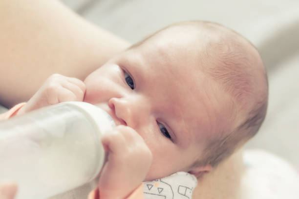 istock Cute newborn boy is drinking milk from bottle 1153491834