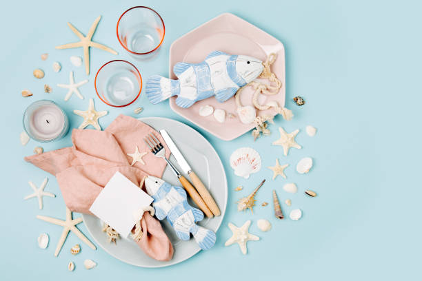 istock Tableware and sea decorations for serving a festive table. Plates, wine glasses and cutlery on blue background. Summer concept. Flat lay, top view 1153496064