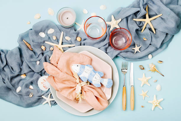 Table Setting and sea decorations for serving a festive table. Plates, wine glasses and cutlery on blue background. Summer concept. Flat lay, top view