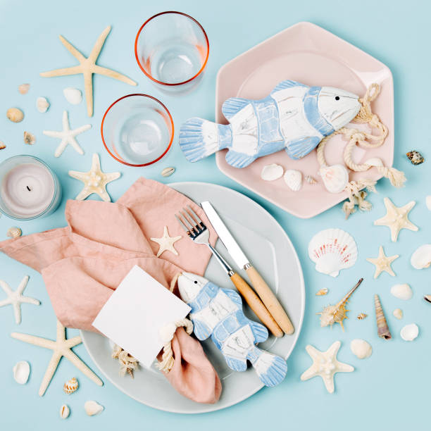 istock Tableware and sea decorations for serving a festive table. Plates, wine glasses and cutlery on blue background. Summer concept. Flat lay, top view 1153496484