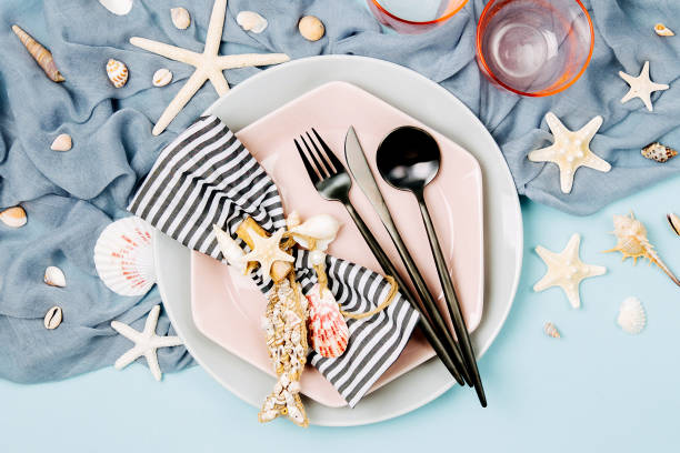 istock Table Setting and sea decorations for serving a festive table. Plates, wine glasses and cutlery on blue background. Summer concept. Flat lay, top view 1153497537
