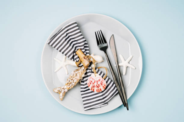istock Tableware and sea decorations for serving a festive table. Plates, wine glasses and cutlery on blue background. Summer concept. Flat lay, top view 1153497595