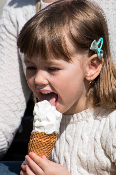 istock Little girl intently licks ice cream cone 1153502817