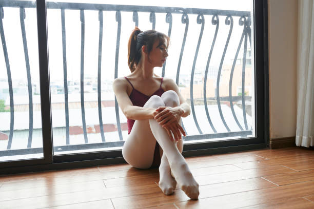 Teenage ballerina practices her stretching routine in studio before practicing ballet, Young dancer warming up in ballet studio, Girl is studying ballet