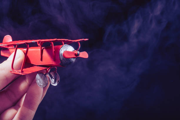 istock Hand holding a toy plane on black background 1153507757