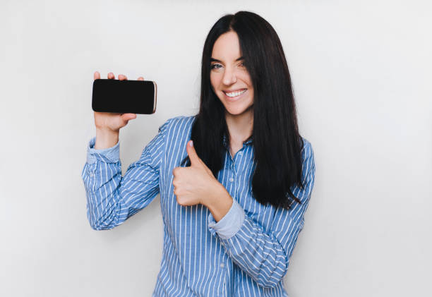 istock Beautiful girl show her smart phone. Empty black screen. Isolate. Device screen. 1153510215