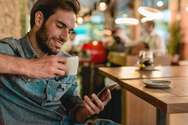 istock a young handsome man sitting in a restaurant and drinking coffee 1153511481