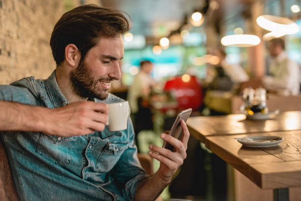 istock a young handsome man sitting in a restaurant and drinking coffee 1153511878