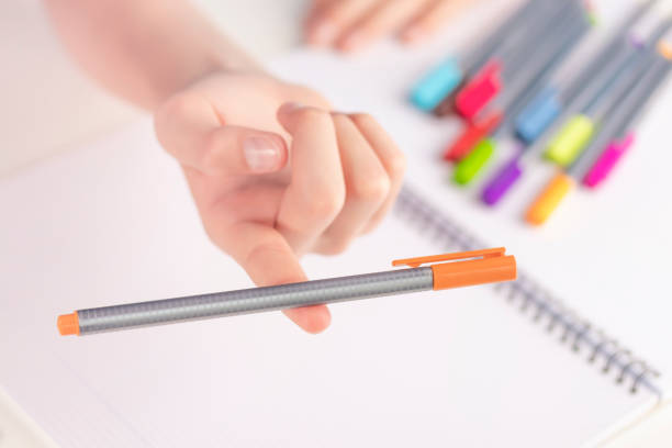 istock Orange felt-tip pen in balance on a child's finger. 1153512394
