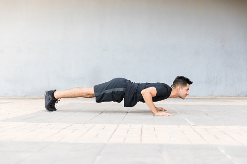 Side view of man warming up and doing push-ups as part of his training