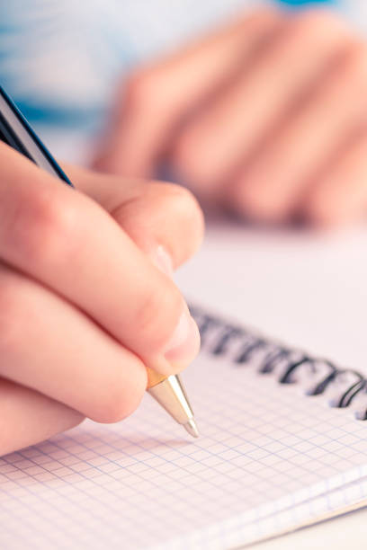 teen writes black yellow pen in a checkered notebook - close up medical test exam people imagens e fotografias de stock