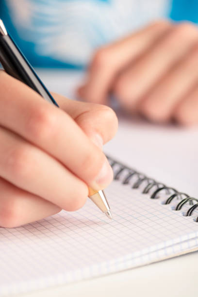 man's hand with a black-gold pen over a clean sheet of checkered notebook - close up medical test exam people imagens e fotografias de stock