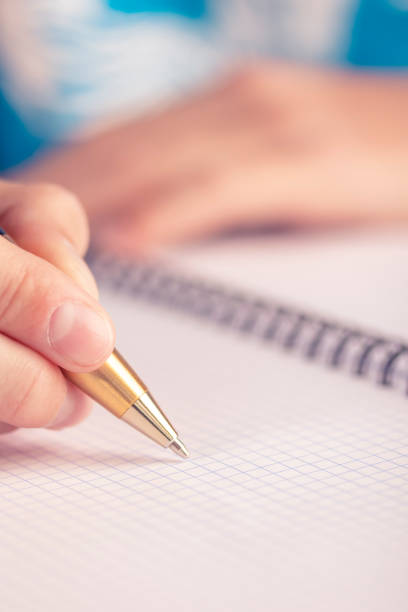 teen writes black yellow pen in a checkered notebook - close up medical test exam people imagens e fotografias de stock