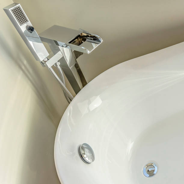 istock Square Glossy white bathtub inside the bathroom with white wall and gray floor 1153515789