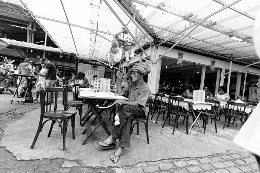 Rio de Janeiro, Brazil - August 25, 2018: Older man awaits his turn to dance at a festival in the market of Sao Cristovao. Image process contain exessive noise or grain. Black and white image