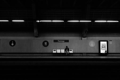 Rio de Janeiro, Brazil - August 25, 2018: Girl waits for the subway at Flamengo station while checking her smartphone. Image process contain exessive noise or grain. Black and white image