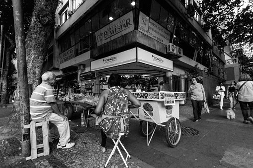 Rio de Janeiro, Brazil - August 24, 2018: Man and woman await customers at their Copacabana street stall. Image process contain exessive noise or grain. Black and white image
