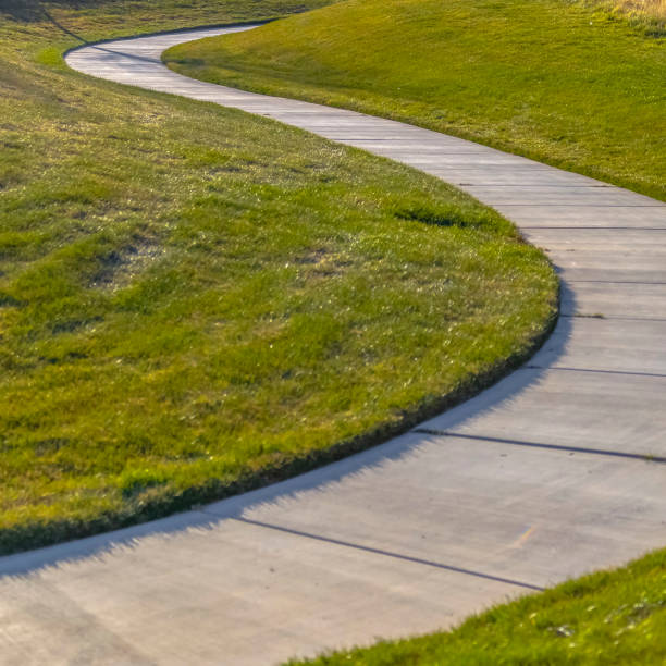 istock Square frame Walkway that winds through a rich grassy field at a park with playground 1153518527