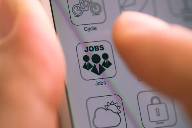 Hand holding smart phone, finger touching job searching app logo on device screen.