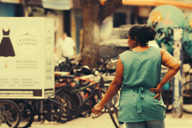 Rio de Janeiro, Brazil - August 22, 2018: Brazilian woman worker smokes on the street while taking a break. Image process contain exessive noise or grain