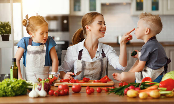 istock mother with children preparing vegetable salad 1153520118