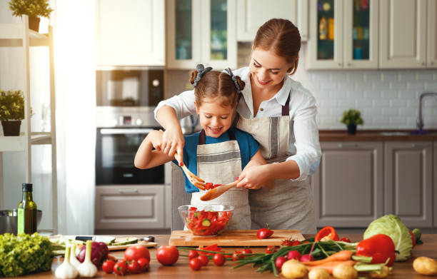 happy family mother with child girl preparing vegetable salad - family mother domestic life food imagens e fotografias de stock