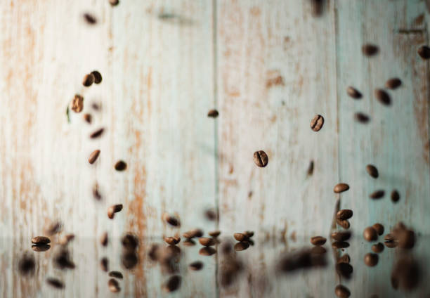 Coffee beans falling on pile against brown reflective background