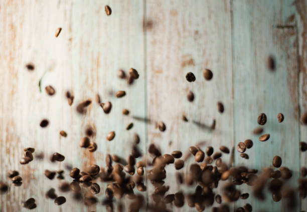 Coffee beans falling on pile against brown reflective background