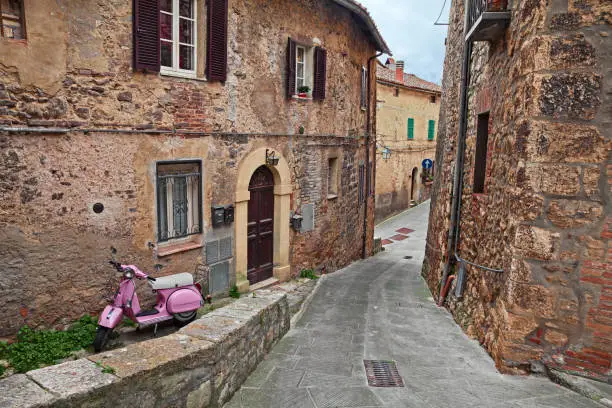 Sarteano, Siena, Tuscany, Italy - April, 7, 2019: picturesque ancient alley in the old town with a pink Vespa scooter
