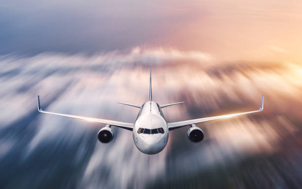 istock Airplane with motion blur effect is flying over low clouds at sunset. Passenger airplane, blurred clouds, colorful sky at dusk. Aerial view of the modern aircraft. Business travel. Commercial plane 1153523546