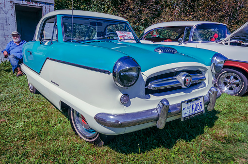 Belmont, Nova Scotia, Canada - September 9, 2017 : Rare 1956 Nash Metropolitan on display at 3rd Annual Belmont Show & Shine in rural Nova Scotia. Man sits and relaxes behind the car.