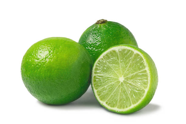 istock Fresh ripe limes, two whole and one half isolated on white background with shadow - image 1153529327