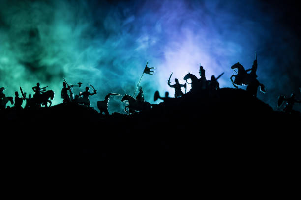 istock Medieval battle scene with cavalry and infantry. Silhouettes of figures as separate objects, fight between warriors on dark toned foggy background with medieval castle. 1153535226