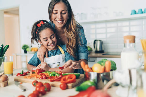 istock Mother and daughter preparing salad together 1153535332
