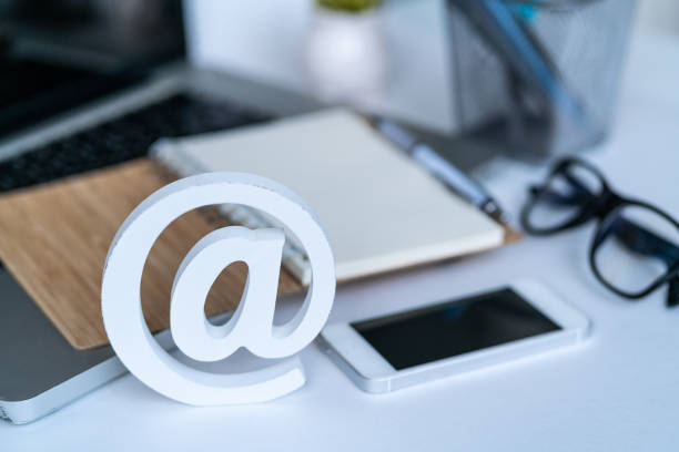 istock Email comcept. Contact us for feedback. Desktop with notepad, smartphone, glasses and email symbol. Top view 1153535509