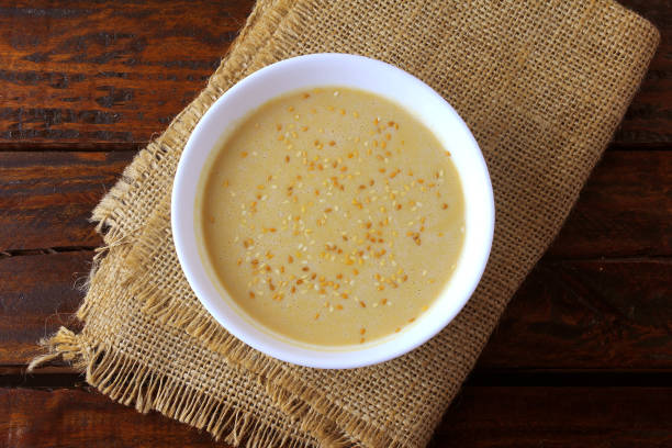 tahini en cuenco de cerámica en mesa rústica de madera-crema o pasta hecha de semillas de sésamo (sésamo) ampliamente utilizado en la cocina de oriente medio - sesame seed spoon scoop fotografías e imágenes de stock