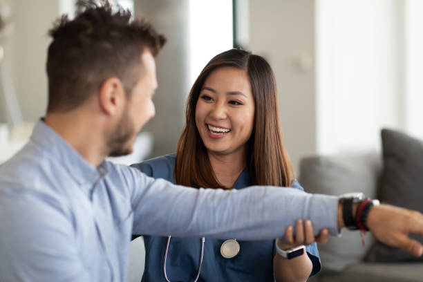 Home visit check-up A young doctor of Asian descent and a young Caucasian patient of  are indoors at the man's home. The doctor is giving him a check-up. occupational therapy photos stock pictures, royalty-free photos & images