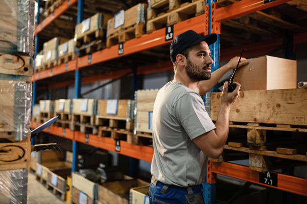 männlicher disponent kommuniziert über walkie-talkie während der arbeit in einem lager. - talkie stock-fotos und bilder