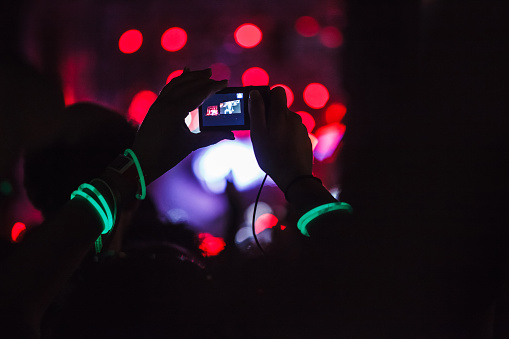 People capturing best memories on a mobile phone during concert party.
