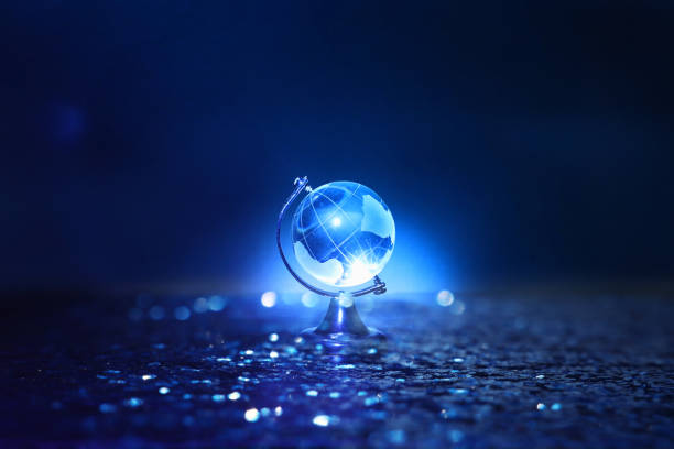istock Small crystal globe in front of dark and dramatic light.global issues concept 1153539662