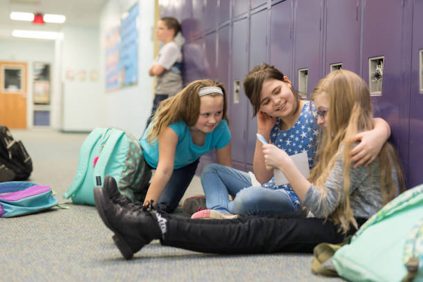 istock Two friends consoling their other friend at an elementary school 1153541394