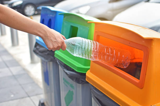istock Woman throwing plastic bottle into recycle bin 1153545859