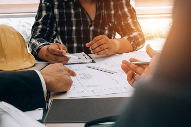 istock engineers pointing to building on blueprint to drawing design building Project in office, construction concept. Engineer concept 1153545924