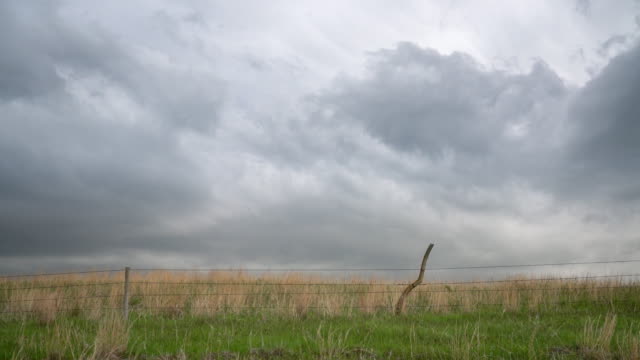 Dark stormy clouds over prairie with a barbed wire cattle fence